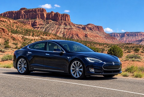 White training sedan parked on a desert highway with red rock cliffs near St. George, Utah